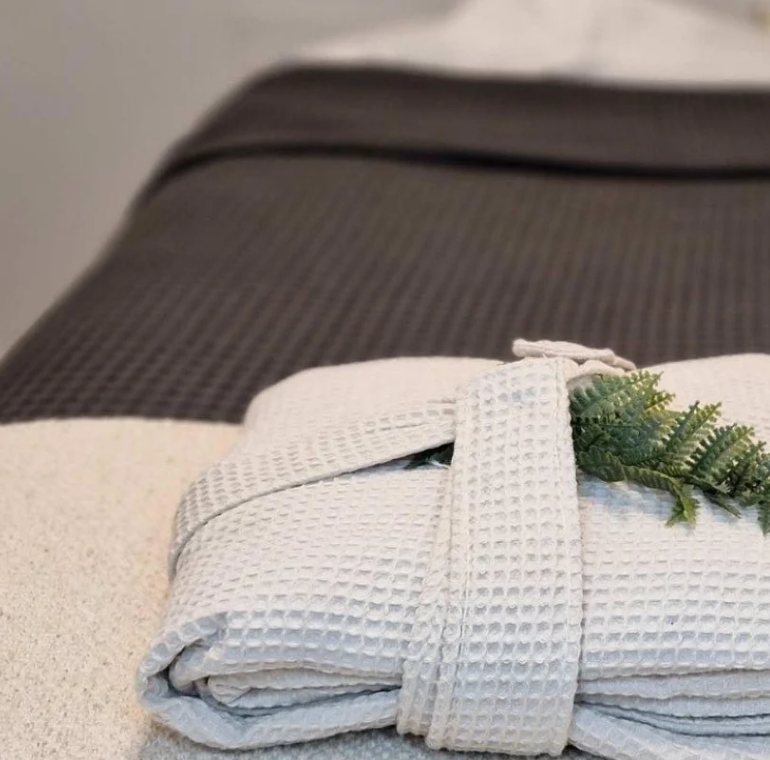 Folded waffle robes and towels laid out on the treatment couch.